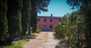 a dirt road in front of a pink building at Casale Saundarya in Sant'Ermo