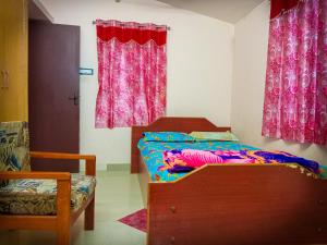 a bedroom with a bed and pink curtains at Comfort Cottage in Yercaud