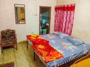 a bedroom with a bed and a chair and a window at Comfort Cottage in Yercaud