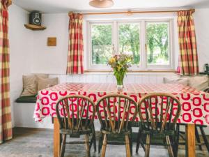 a red table with chairs and a vase of flowers at Shute Cottage in Manorbier