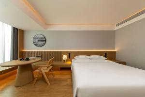 a hotel room with a bed and a table at Floral Hotel Banlan Cangzhou Convention and Exhibition Center High-speed Railway West Station in Zhifangtou