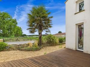 une maison avec un palmier dans la cour dans l'établissement Maison familiale et colorée avec jardin pour 6, à Saligottière