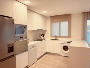 a kitchen with white cabinets and a washer and dryer at Apuliaapartments in Apúlia