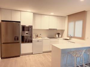 a kitchen with white cabinets and a stainless steel refrigerator at Apuliaapartments in Apúlia +18 photos