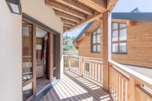 a wooden balcony of a log house with glass doors at Le Refuge du Pic in L'Alpe-d'Huez