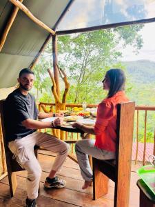 Un hombre y una mujer sentados en una mesa en una tienda de campaña. en Ella Soul Nest Glamping Tent for Nature Lovers, en Ella