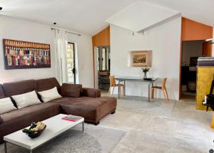 a living room with a brown couch and a table at Les Cerisiers maison bertuli climatisé, Piscine chauffée, lit King size, classé 5 étoiles in Oppède