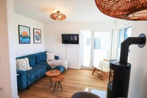 トッセンスにあるWatt n` Kokolores - Ferienhaus mit Terrasse und Infrarotsaunaの青いソファとテーブルのあるリビングルーム