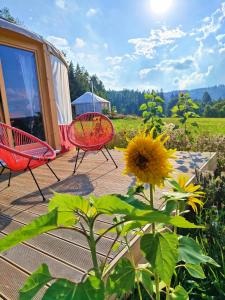 a deck with two chairs and a sunflower next to a tent at Glamping Niebiańska Osada Jurty Dolnośląskie in Polanica-Zdrój