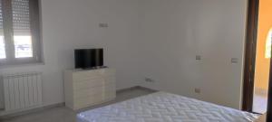 a white bedroom with a bed and a tv on a dresser at Bed and Bike in Vasto
