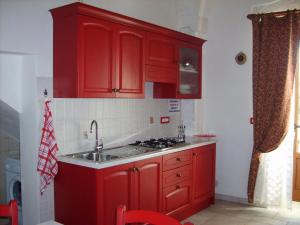 cocina roja con fregadero y armarios rojos en La Piccola Masseria, en Cisternino