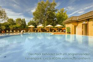 a large swimming pool with chairs and umbrellas at Golf 'n Wave Aktivresort Fehmarn in Fehmarn