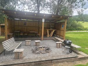 a patio with a barbecue and a grill and a bench at Retro chatky Hůrka Lipno in Horní Planá