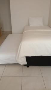 een slaapkamer met twee witte bedden en een tegelvloer bij opulen view in Rawabugel