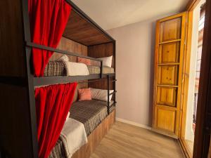 a bedroom with two bunk beds with red curtains at Posada de la Luna in Granada