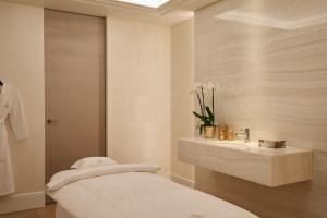 a bathroom with a white sink and a white bed at The Woodward - Auberge Resorts Collection in Geneva