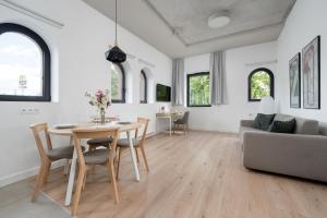 una sala de estar con una mesa, sillas y un sofá en PIEKARNIA Żywa Kultura Atmospheric Apartments in Wrocław by Noclegi Renters, en Wroclaw 50 fotos más