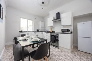 eine Küche mit weißen Geräten sowie einem Tisch und Stühlen in der Unterkunft Charming 3-BR Home Near Historic Town Centre in Bishop Auckland