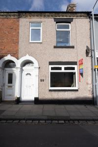 ein Backsteingebäude mit zwei weißen Türen auf einer Straße in der Unterkunft Charming 3-BR Home Near Historic Town Centre in Bishop Auckland