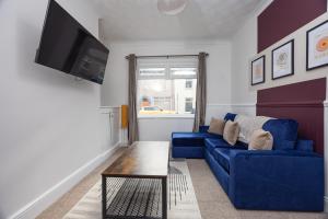 ein Wohnzimmer mit einem blauen Sofa und einem Fernseher in der Unterkunft Charming 3-BR Home Near Historic Town Centre in Bishop Auckland