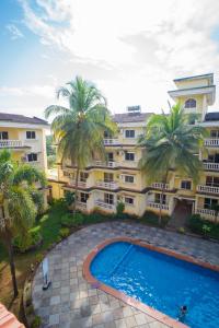 un immeuble d'appartements avec piscine et palmiers dans l'établissement Ocean Whisper Goa, à Jāmb