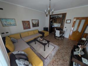 Una sala de estar con un sofá amarillo y una mesa. en Inn Cloud Gjirokaster, en Gjirokastra