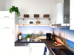 a kitchen with a sink and a beach mural on the wall at Fewo Anker in der Villa Victoria in Graal