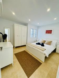 a white bedroom with a large bed and a desk at Bungalow Mesana 27 in Playa Honda