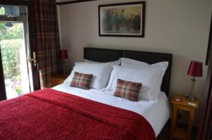 a bedroom with a bed with a red blanket and two pillows at Smithfield Farm Bed & Breakfast in Builth Wells