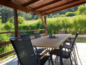 a wooden table and chairs on a patio with a view at River Lodge Jesenica in Lička Jesenica