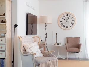 a living room with a chair and a clock on the wall at Nausikaa's- Fleur de Lis in Groß Schwansee