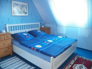 a bedroom with a bed with blue sheets and a window at Ferienwohnung Luise in Carolinensiel
