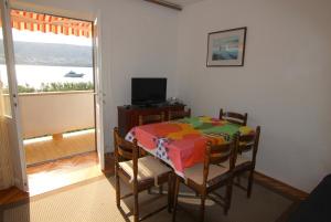 Un comedor con mesa y sillas y una ventana. en By the sea apartment, en Pag