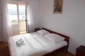 Un dormitorio con una cama con sábanas blancas y una ventana. en By the sea apartment, en Pag