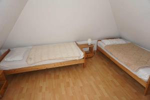 two beds in a small room with wooden floors at Ferienhaus Fischerstraße 11 in Carolinensiel +3 photos