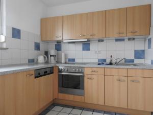a kitchen with wooden cabinets and a stove top oven at Haus Strandkrabbe in Hooksiel +6 photos