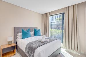 ein Schlafzimmer mit einem Bett mit blauen Kissen und einem Fenster in der Unterkunft The Terrace101- 2 Bed, Sandton in Johannesburg
