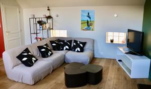 a living room with a couch and a tv at La Marée Grand appartement à 5 min du Touquet in Étaples