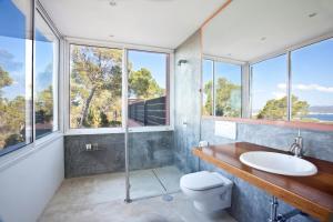 une salle de bain avec un lavabo et des toilettes et des fenêtres dans l'établissement Stunning Seaside Oasis in Ibiza, 1049, à Port des Torrent 46 autres photos