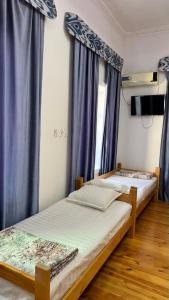 two beds in a room with blue curtains at Silk Road Guest House in Bukhara +19 photos