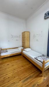 two beds in a room with wooden floors and drawings on the wall at Silk Road Guest House in Bukhara