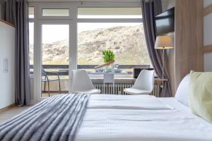 een slaapkamer met een bed, een tafel en stoelen bij Lister Duenennest in List