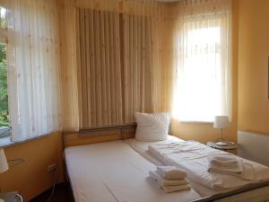a bedroom with a white bed with towels on it at Dünenschloss - 02-29 in Kühlungsborn +11 photos