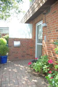 a brick house with a window and some flowers at Schönes Wohnen am Nordseestrand in Wyk auf Föhr