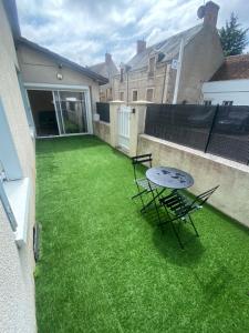 a patio with a table and chairs on the grass at 80 m2 meublé RDC in Saint-Benoît-sur-Loire