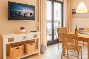 ein Wohnzimmer mit einem Tisch und einem Fernseher an der Wand in der Unterkunft Villa Baltic Sun in Ostseebad Sellin