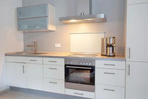 eine Küche mit weißen Schränken und einem Herd mit Backofen in der Unterkunft Villa Baltic Sun in Ostseebad Sellin