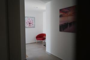 Una habitación con una silla roja y dos cuadros. en Villa Novak, en Rab