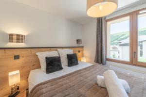 ein Schlafzimmer mit einem großen Bett und einem großen Fenster in der Unterkunft Alpe d'Huez Houses - Chez Cathy - Fermes de l'Alpe - Fabuleux 2 chambres neuf pour 6 personnes in L'Alpe-d'Huez