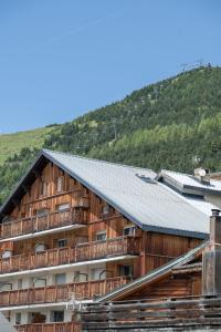 ein Holzgebäude mit einem Berg im Hintergrund in der Unterkunft Alpe d'Huez Houses - Chez Cathy - Fermes de l'Alpe - Fabuleux 2 chambres neuf pour 6 personnes in L'Alpe-d'Huez